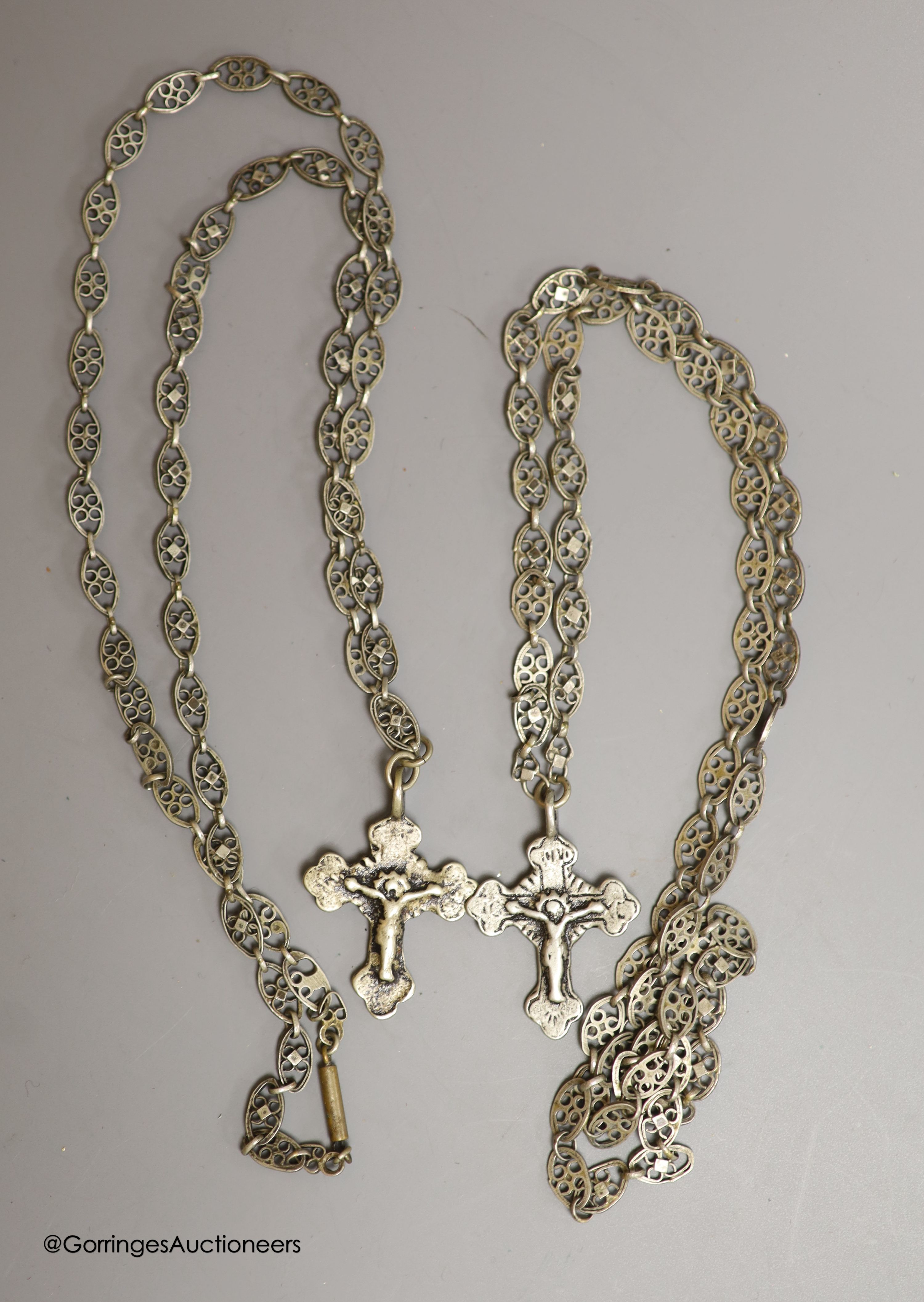 Two Russian white metal crucifixes on pierced oval link neck chains and a cast brass scribes ink pot.
